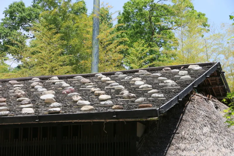 栗板の上に５００個ほどの石が並べられている板葺屋根