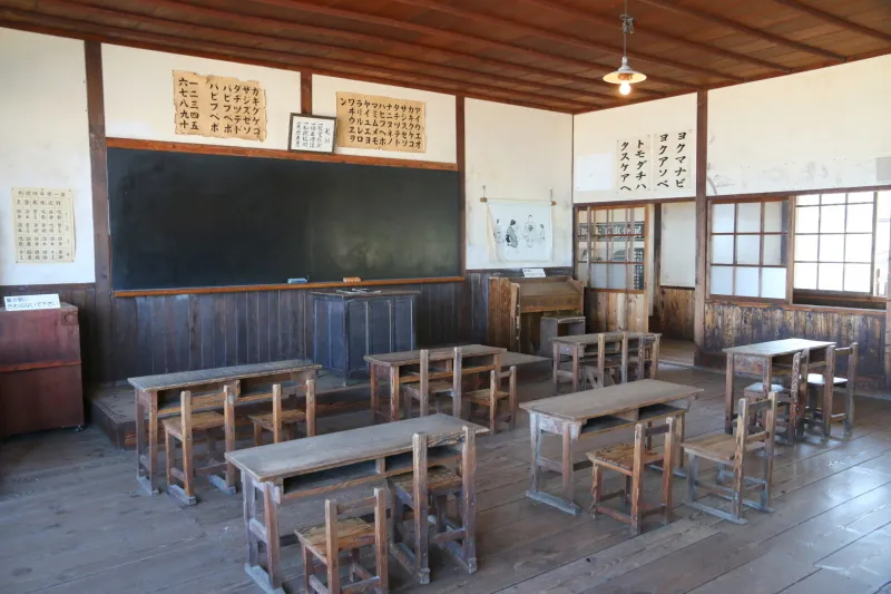 校舎は室内を見学することもでき、小さな机の並ぶ教室の様子 