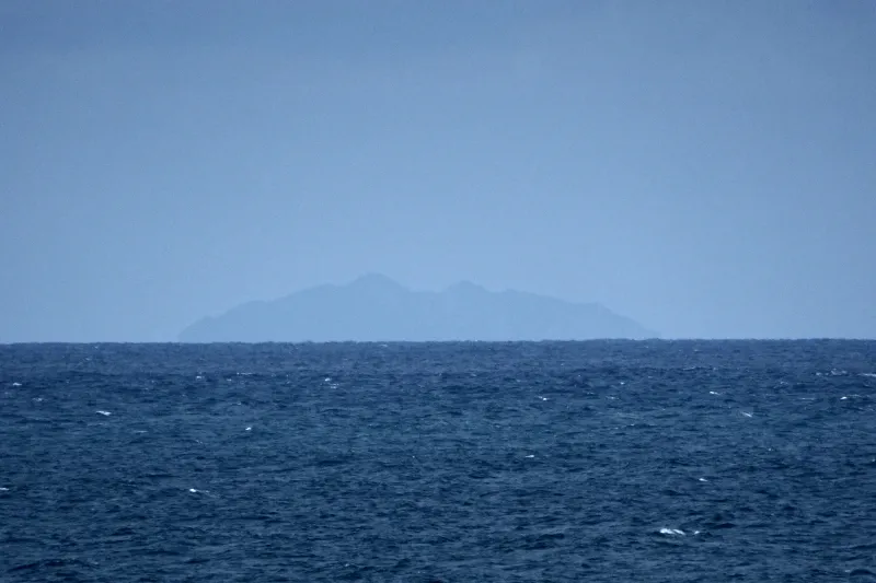 望遠レンズで撮影すると見える水平線に浮かぶ沖ノ島 