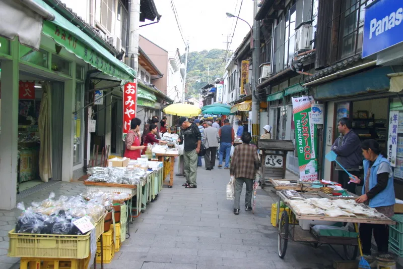 魚介類や特産品を中心に、狭い通りに様々なお店が並ぶ光景 